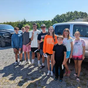 A group of young volunteers standing together in the gravel lot outside.